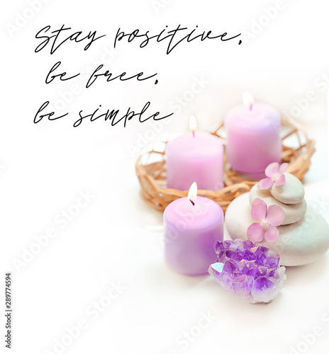 Stay positive, be free, be simple - motivation quote. amethyst geode crystal, candles, flowers hydrangea, spa stones on white background. Spa therapy composition. soft selective focus