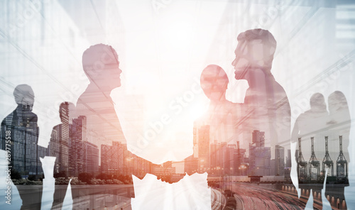 Double exposure image of many business people conference group meeting on city office building in background showing partnership success of business deal. Concept of teamwork, trust and agreement.