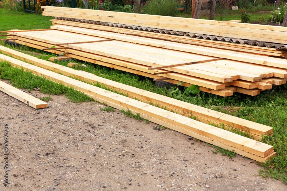 Fresh, rough, wooden boards lie on the street, on the construction site. Construction of the roof. Fresh, rough, wooden boards lie on the street, on the construction site. Construction of the roof.