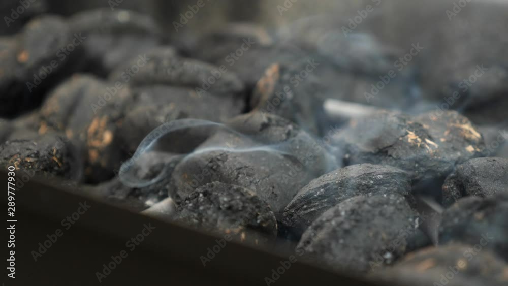 Smoke comes from charcoal briquettes as they heat in a grill for a cookout Smoke comes from charcoal briquettes as they heat in a grill for a cookout
