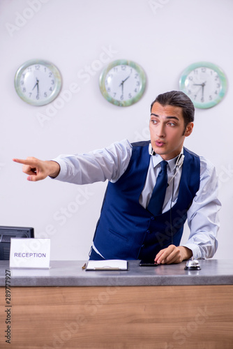 Young man receptionist at the hotel counter