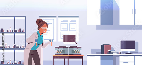 scientist holding test tubes with blood samples woman in uniform using analyzer medical machine research science medicine concept modern laboratory interior portrait horizontal