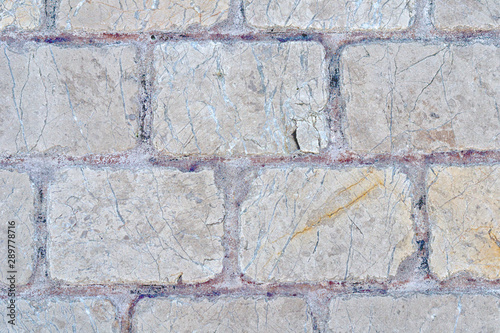 An old wall piled of gray stone blocks.