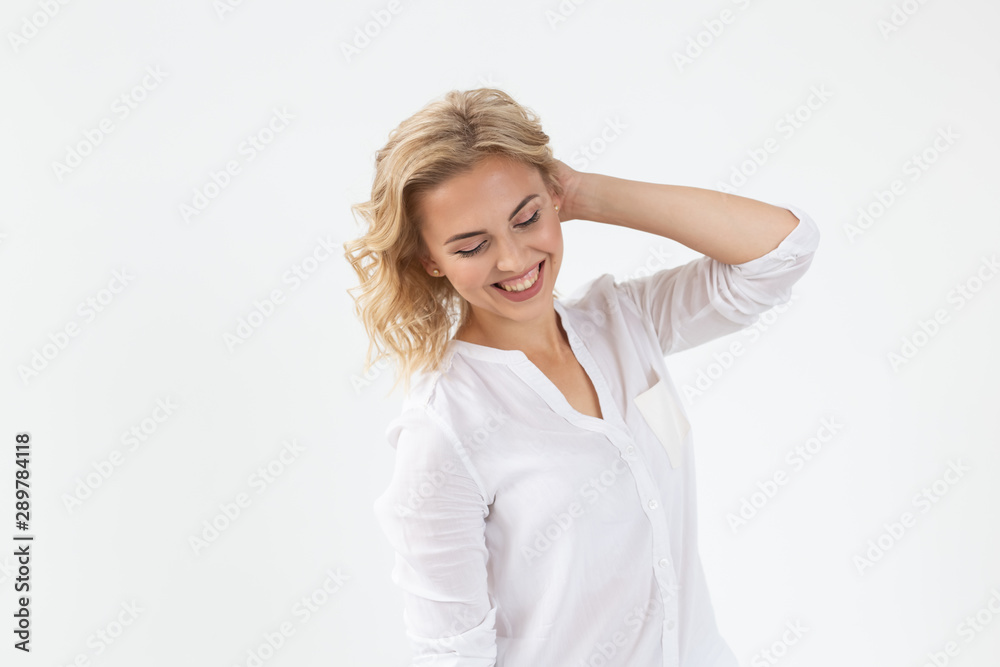 Smiling charming young blonde woman standing against a white background. Concept of carefree young girl Smiling charming young blonde woman standing against a white background. Concept of carefree young girl