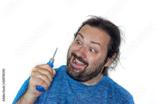 Crazy man with tousled hair and unshaven with a screwdriver in his hands