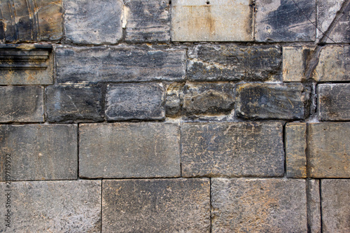 Background with a wall of old masonry with blackened stones