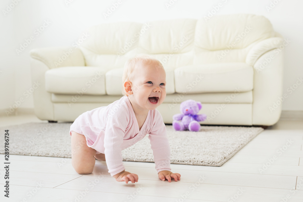 Adorable baby girl learning to crawl in white sunny room. Adorable baby girl learning to crawl in white sunny room.