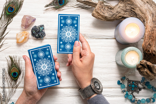 Fortune teller woman and a blue tarot cards over white wooden table background.