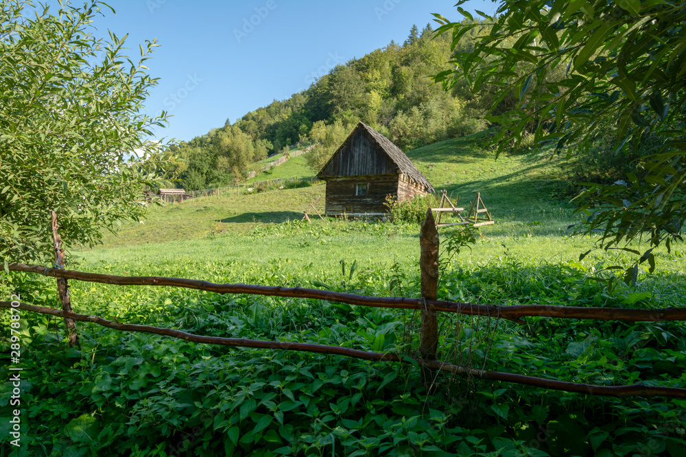 Beautiful peasant house on the field with grass and wooden fence