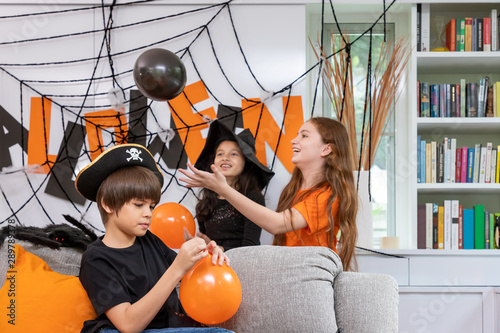 Children boy and  girls are blowing an dplaying balloon to prepare Halloween party decoration