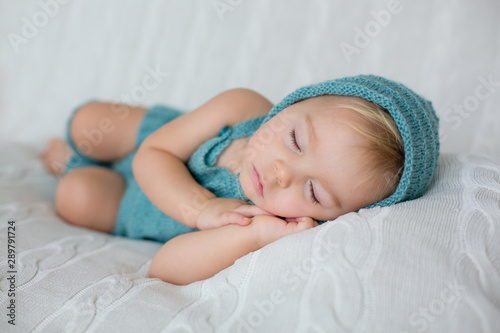 Sweet toddler boy, sleeping with teddy bear toy, cute knitted outfit