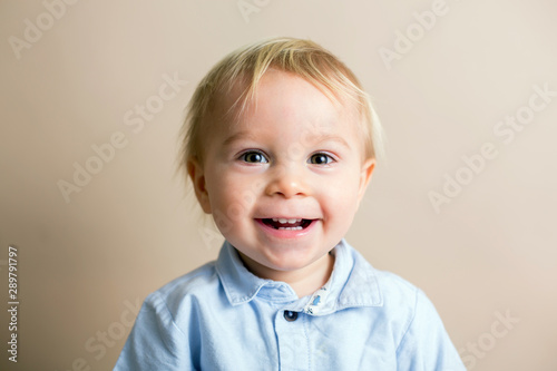 Portrait of cute baby toddler boy, isolated on beige background