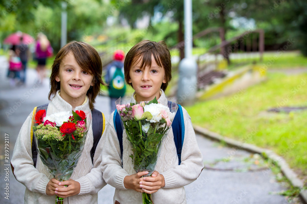 Obraz premium Happy school children, holding bouquet of flowers, going to school first day