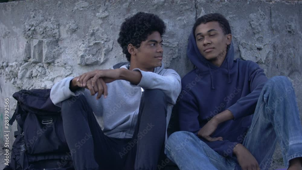 Carefree relaxing male teens looking each other sitting outdoors, adolescence Carefree relaxing male teens looking each other sitting outdoors, adolescence