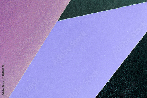 Multicolored sheets of paper on a dark leather background close up