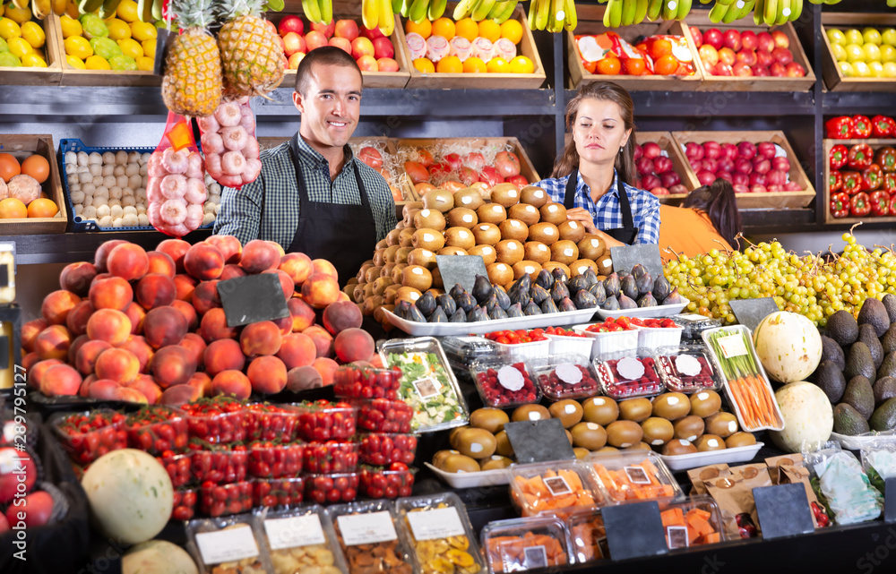 Man selling fresh kiwi and other fruits on supermarket