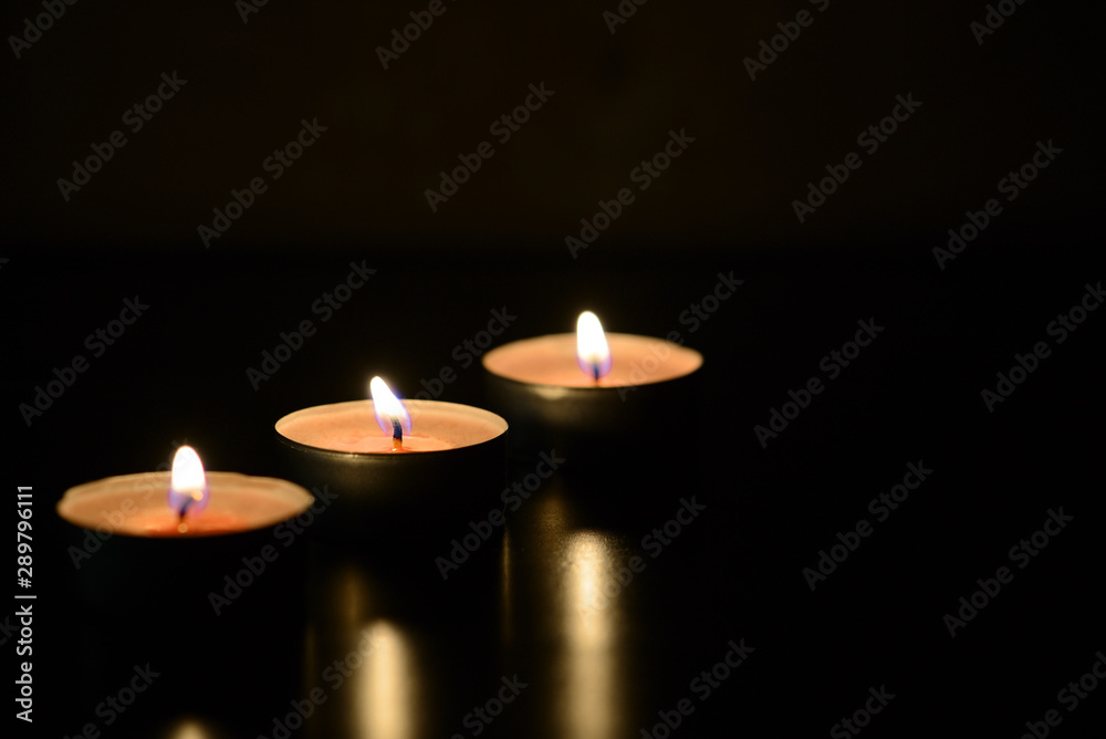Three burning candles close up in the darkness. Mystery background Three burning candles close up in the darkness. Mystery background