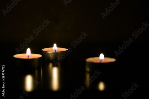 Three burning candles close up in the darkness. Mystery background