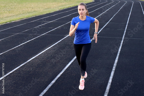 Runner athlete running on athletic track training her cardio in stadium. Jogging at fast pace for competition © ty