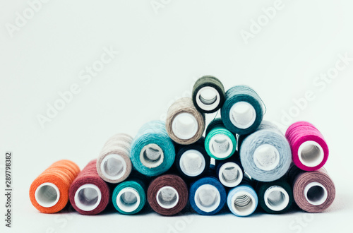 Colored sewing thread coils on white background with copy space for text.