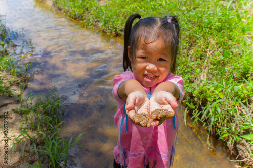 Asian Children playing  barefoot in stream water, play mud and sand. photo