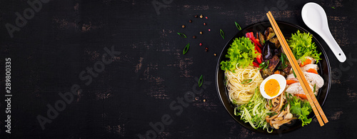 Fotografie Japanese ramen soup with chicken, egg, shimeji mushrooms and eggplants on dark wooden background