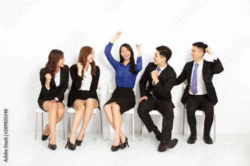 happy asian business people sitting on the chairs in a row
