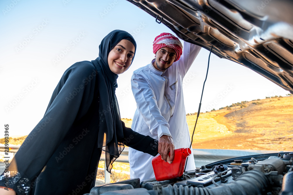 Arabic woman and her husband pouring oil in the car engine Arabic woman and her husband pouring oil in the car engine