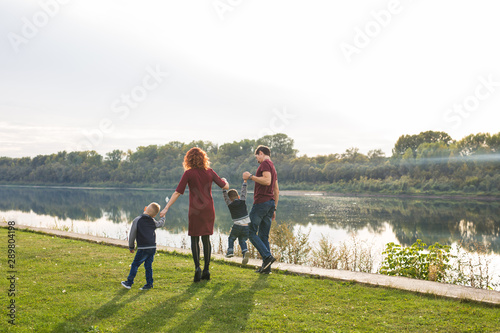 Parent, childhood and nature concept - Family playing with two sons by the water