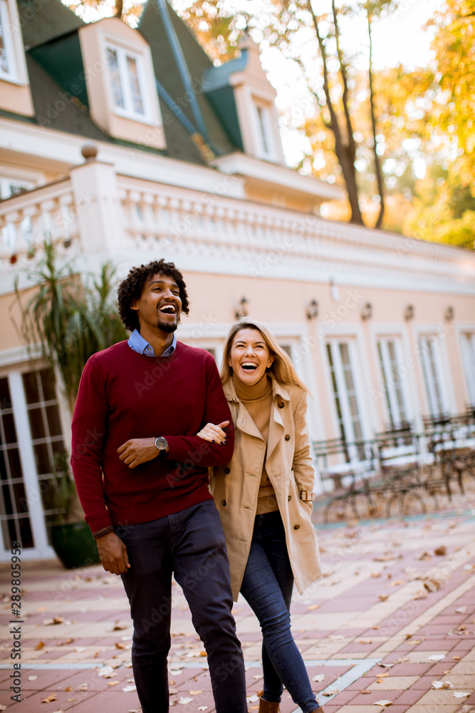 Positive multiracial couple walk on the street at autumn
