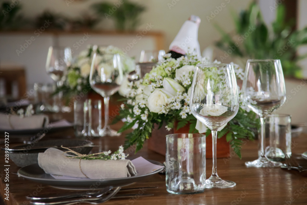 The beautiful arrangement on the wooden table, white roses and ceramic plates. Boho chic wedding table setting. 