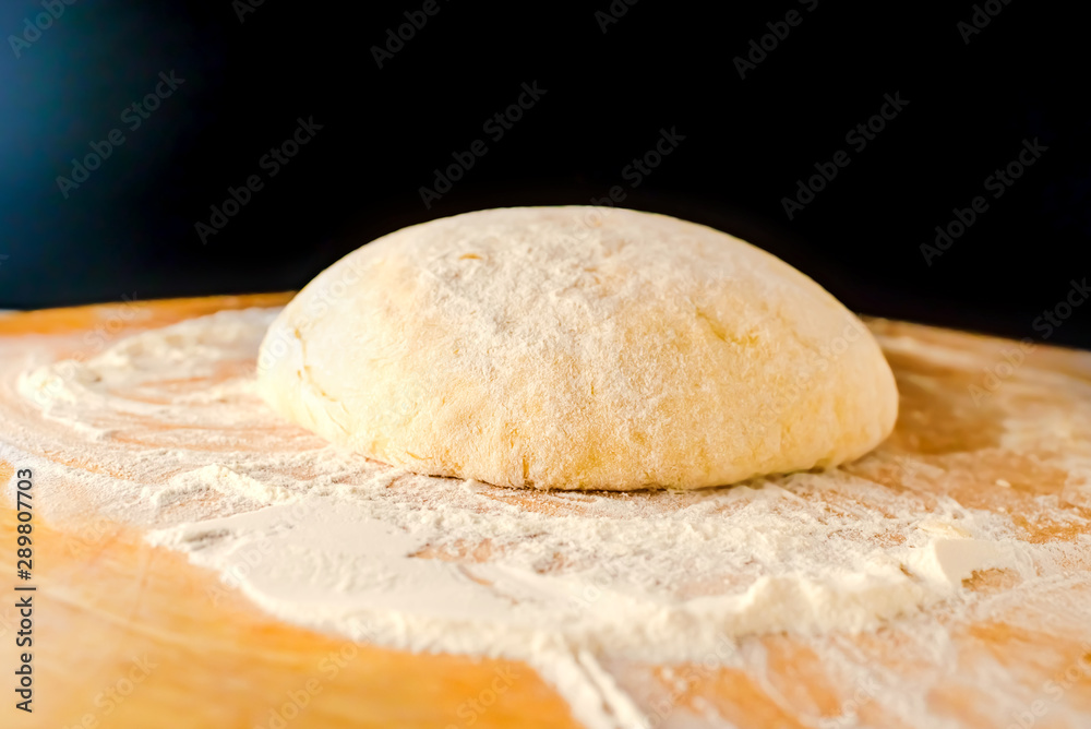 Dough on a wooden Board and with a black background. Gentle dough for baking Dough on a wooden Board and with a black background. Gentle dough for baking