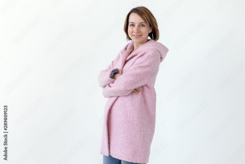 Positive young pretty woman posing in a scarf and a pink coat on a white background. Concept of autumn spring clothes. Advertising space. Positive young pretty woman posing in a scarf and a pink coat on a white background. Concept of autumn spring clothes. Advertising space.