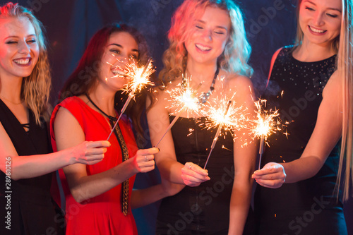 Party, holidays, new year, christmas and nightlife concept - happy young women dancing at night club disco, close-up