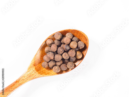 Allspice (Jamaica pepper) in the wooden spoon diagonally on white background
