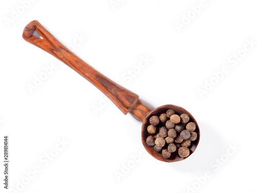 Allspice (Jamaica pepper) in wooden spoon diagonally on white background
