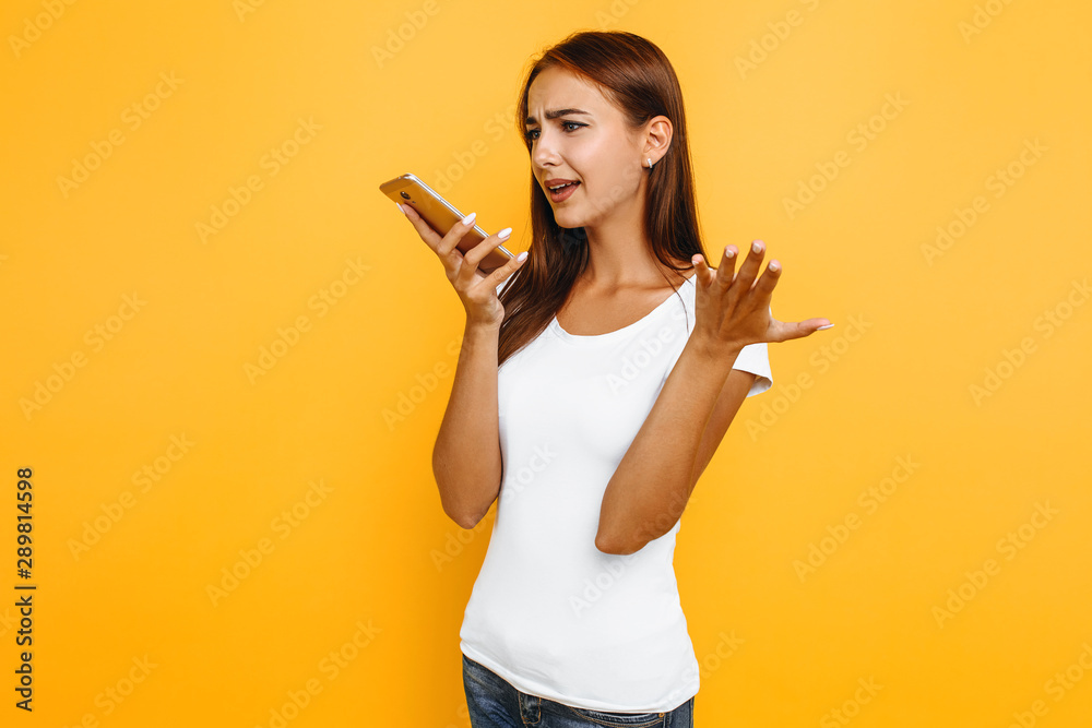 Young sad woman talking on the phone, frustrated, on yellow background Young sad woman talking on the phone, frustrated, on yellow background