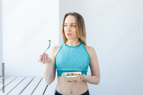 healthy eating  dieting and fitness concept - young woman eating vegetable and meat after workout