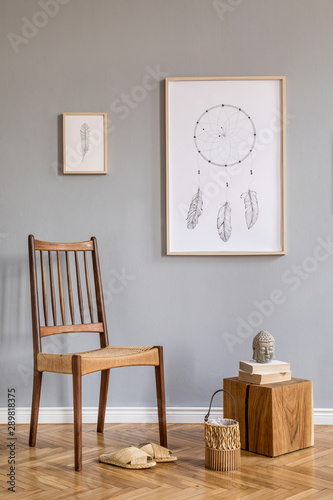 Stylish bohemian interior design of living room with retro chair, rattan slippers, wooden cube, bag, mock up poster frames and elegant accessories. Gray background walls. Modern home decor. Template.