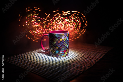 Beautiful eastern style textured ceramic cup of coffee (or tea) with smoke over dark toned background.