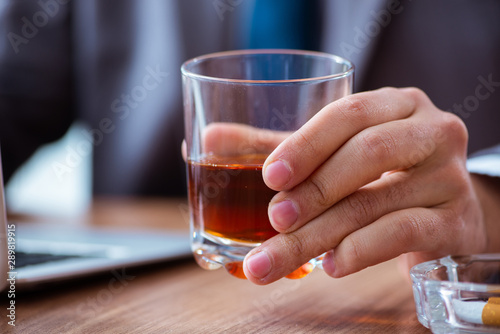 Male employee drinking alcohol and smoking cigarettes at workpla