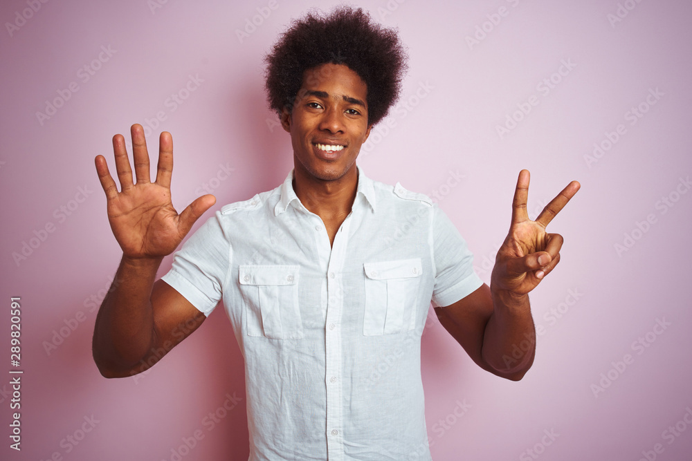 Young american man with afro hair wearing white shirt standing over isolated pink background showing and pointing up with fingers number seven while smiling confident and happy. Young american man with afro hair wearing white shirt standing over isolated pink background showing and pointing up with fingers number seven while smiling confident and happy.