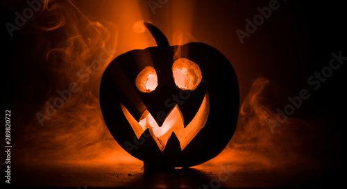 Halloween pumpkin smile and scrary eyes for party night. Close up view of scary Halloween pumpkin with eyes glowing inside at black background. photo