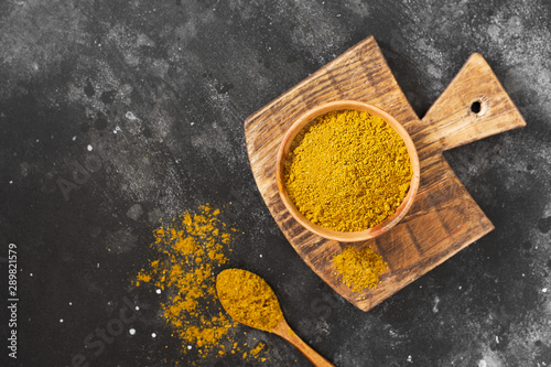 Curry powder in a wooden bowl on a wooden table. Variety of spices. Top view