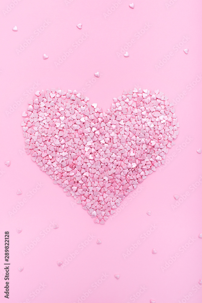 Pink background. Pink hearts on a pink background. Hearts sprinkles. Flat lay style. Top view. Sweet background. Confetti.