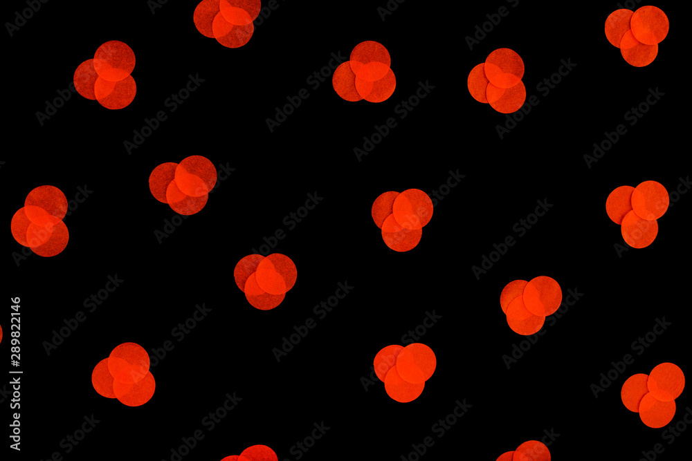 Halloween holiday background with orange confetti on an isolated black