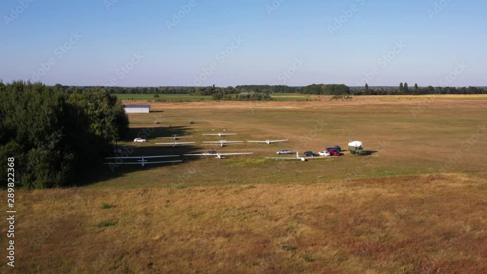 Aerial drone parallax shot of fixed wing gliders parked in the middle of an airfield in the middle of a meadow in the Ukrainian countryside Aerial drone parallax shot of fixed wing gliders parked in the middle of an airfield in the middle of a meadow in the Ukrainian countryside