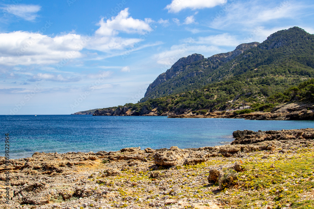 Bucht auf der Halbinsel La Victoria, Mallorca mit Bergrücken im Hintergrund blaues Wasser und Felsen im Meer