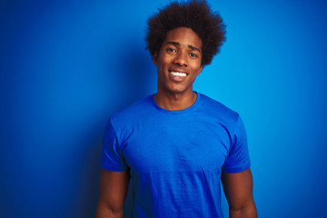 African american man with afro hair wearing t-shirt standing over isolated blue background with a happy and cool smile on face. Lucky person.