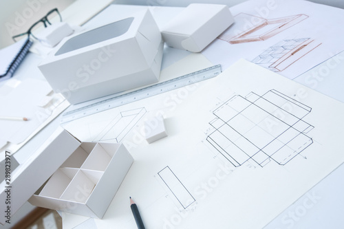Development design drawing packaging. Desktop of a creative person making cardboard boxes. photo